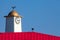 Vibrant seaside pier clock tower with weathervane.