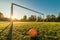 Vibrant soccer ball off centered in front of soccer goal at sunrise