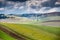 Vibrant , striped green agricultural field at springtime, dark dramatic stormclouds