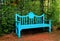 Vibrant turquoise blue colored wooden bench on terracotta brick pathway