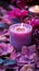 Vibrant violet candle amidst delicate pink and purple flower petals