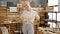 Vibrant young blonde female carpenter, smiling brightly and confidently, standing in her carpentry workshop, proud of her