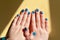 Vibrantly painted blue fingernails in a line with interlocking thumbs