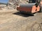 Vibrating roller compresses the soil of a road surface during road construction works