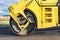 Vibratory road roller lays asphalt on a new road under construction. Close-up of the work of road machinery. Construction work on