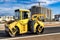 Vibratory road roller lays asphalt on a new road under construction. Close-up of the work of road machinery. Construction work on