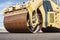 Vibratory road roller lays asphalt on a new road under construction. Close-up of the work of road machinery. Construction work on