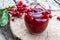 Viburnum fruit jam in a glass jar on a wooden table near the ripe red viburnum berries. Source of natural vitamins. Used in folk