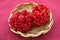 Viburnum fruits in a wicker straw plate on a red tablecloth on the table. Fresh berries. Vegetarian food concept
