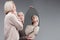 Vicious blonde girl in light knitted sweater posing while looking in mirror