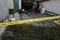 Victim of a violent crime in a backyard of residental house in evening. Dead man body under the yellow police line tape and