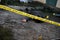 Victim of a violent crime in a backyard of residental house in evening. Dead man body under the yellow police line tape and