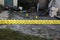 Victim of a violent crime in a backyard of residental house in evening. Dead man body under the yellow police line tape and