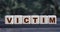 VICTIM - word on wooden cubes on blurred camouflage background