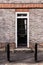 Victorian black external wooden door with glass panels on a classic grey brick wall