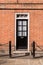 Victorian black external wooden door with glass panels on a classic red brick wall