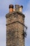 Victorian domestic chimney with four assorted chimney-pots against a clear blue sky background. Close up