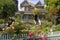 victorian house with lush garden and trellis, surrounded by blooming flowers