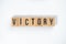 ` VICTORY ` text made of wooden cube on  White background