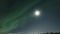 Video of brilliant green Aurora shining over Swedish frozen lake and winter landscape, light rays from a full moon in different