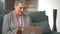 Video call concept, lovely elderly woman with short grey haircut, smiling, chatting with family, using a laptop for