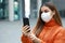 Video calling and Social Distancing. Beautiful young woman in city street wearing protective mask using mobile phone to make video