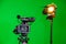 A video camera and a spotlight with a Fresnel lens on a green background. Filming in the interior. The chroma key