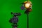 A video camera and a spotlight with a Fresnel lens on a green background. Filming in the interior. The chroma key