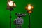 A video camera and a spotlight with a Fresnel lens on a green background. Filming in the interior. The chroma key