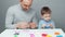 Video of dad and son sculpting toys from plasticine on gray background
