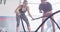 Video of diverse female fitness trainer encouraging woman battling ropes working out at a gym