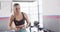 Video of diverse female fitness trainer encouraging woman doing squats with kettlebell weight at gym
