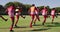 Video of diverse group of male football players warming up on field, running and stretching