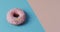 Video of donut with icing on blue and pink background