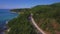 Video from the drone flying along the coast. A road passes along the shore. Montains and foresst on the ocean coast.