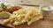 Video of fish and chips with lemon wedge and dip on wooden board, on rustic table