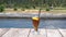 Video footage of a glass of iced lemon tea with a straw  on the edge of a small pond with a fountain and a wonderful view to rice