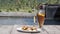 Video footage of a glass of iced lemon tea with a straw and plate of fried bananas with chocolate on the edge of a small pond with