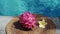 Video footage of red dragon fruit on the edge of swimming pool with white tropical flowers frangipani, bubbling pool blue water