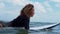 Video footage of surfer girl on white surf board in blue ocean pictured from the water