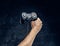 Video game console controller in gamer hand against the background of the dark wall