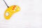 Video game console GamePad on a white wooden table. Yellow retro GamePad.