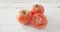 Video of halved and whole fresh red tomatoes on white rustic background