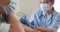 Video of hands of biracial female doctor vaccinating caucasian senior man