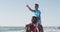 Video of happy african american father carrying son on arms and walking on beach