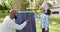 Video of happy african american father explaining solar panel to daughter in autumn garden