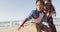 Video of happy african american father learning son how to skateboard on promenade