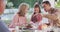 Video of happy caucasian father, daughter and grandparents talking at outdoor dinner table