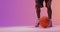 Video of low section of biracial male basketball player with ball on orange to pink background