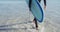 Video of low section of caucasian man in wetsuit with surfboard walking out of sea on sunny beach